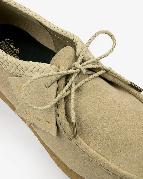 Close-up of a beige ALD / Clarks Suede Wallabee with braided laces and gold AIME LEON DORE text on the tag.