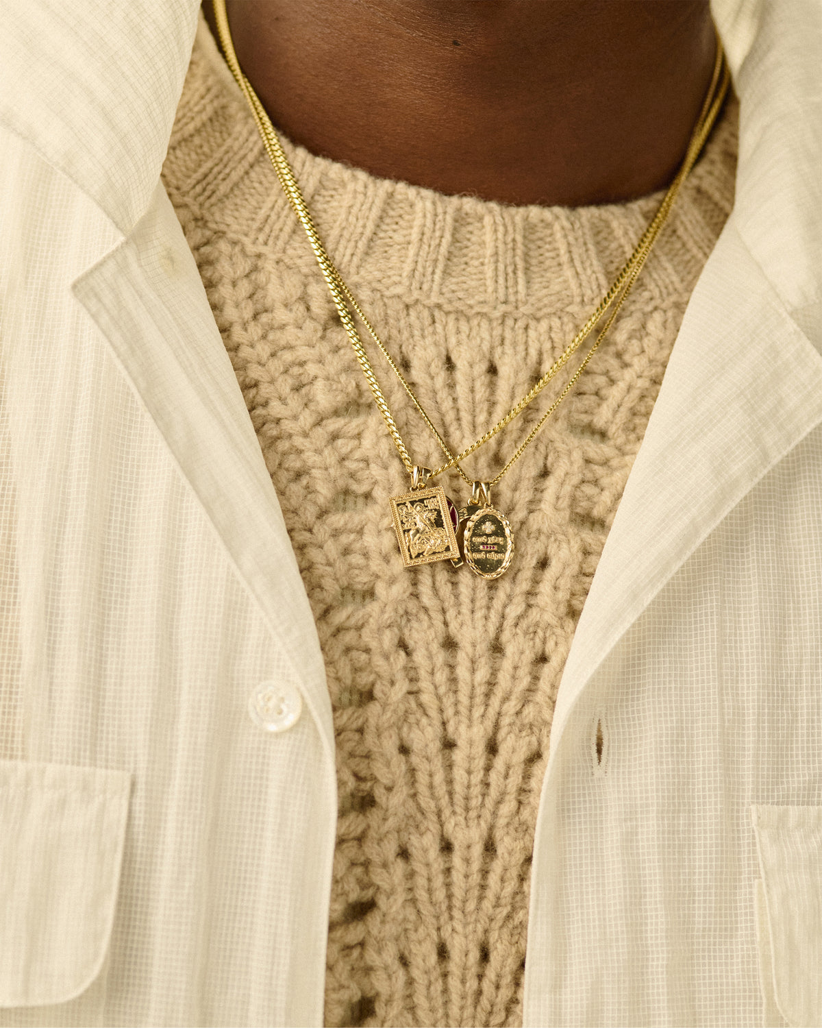 Close-up of a person wearing a 14Kt Gold Saint George Pendant over a cream knit sweater and button-up shirt.