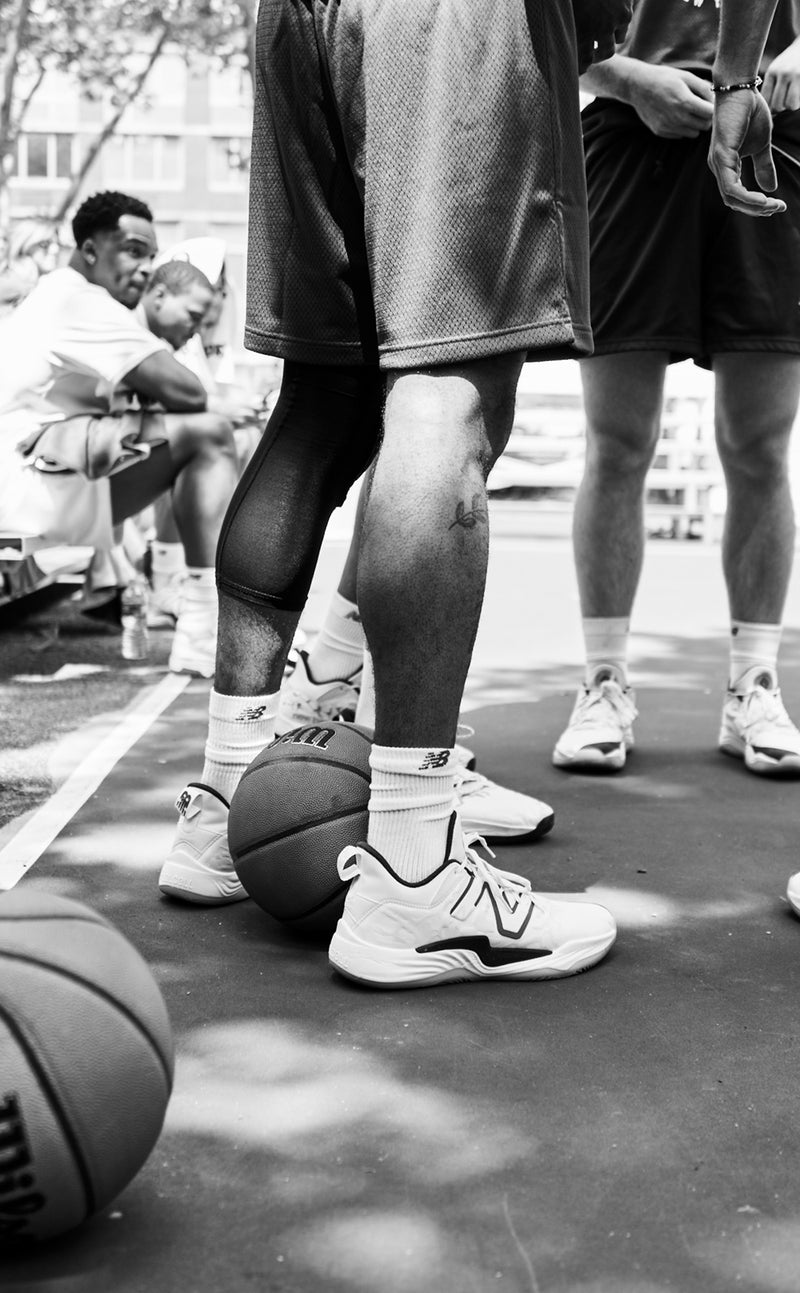 Men huddling on basketball court in front of spectators on bleachers 