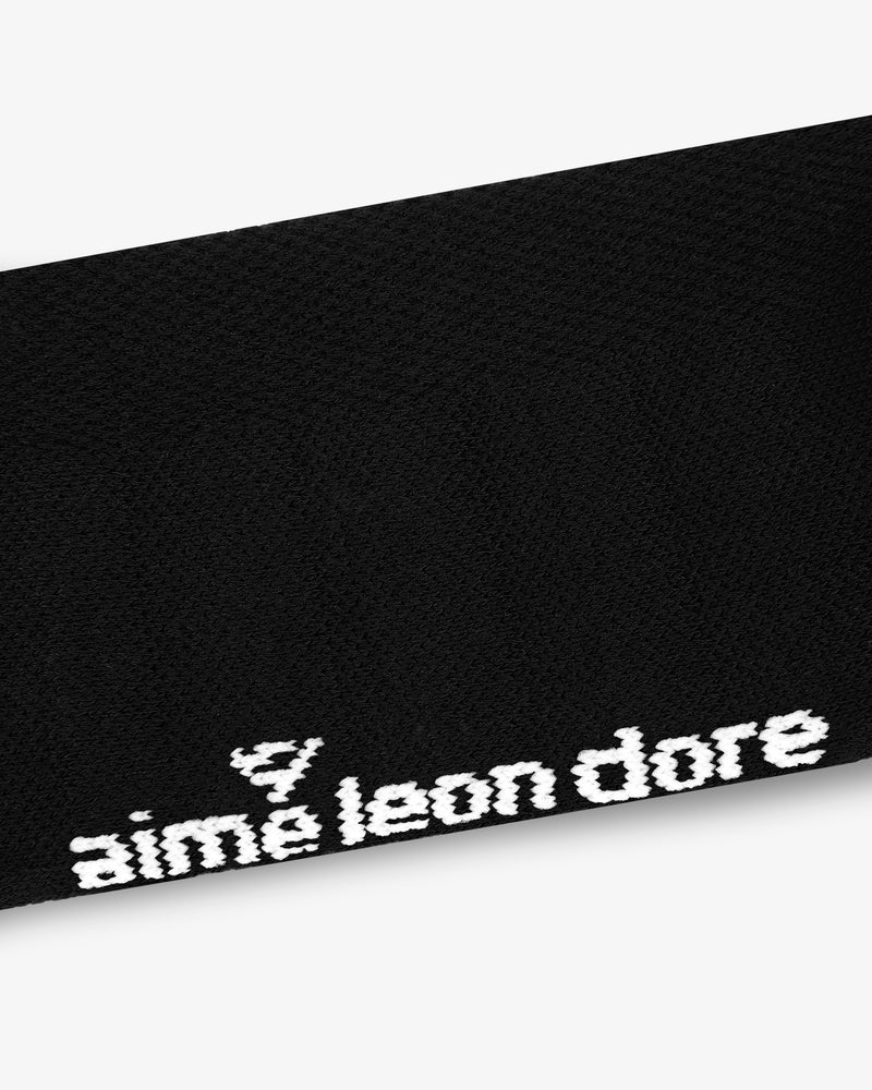 Close-up of black ALD Golf Performance Ankle Sock with aimé leon dore embroidered in white near the edge.