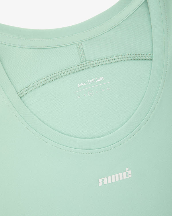 Close-up of the Aimé Performance Tank Top in light green with AIMÉ LEON DORE branding printed in white.