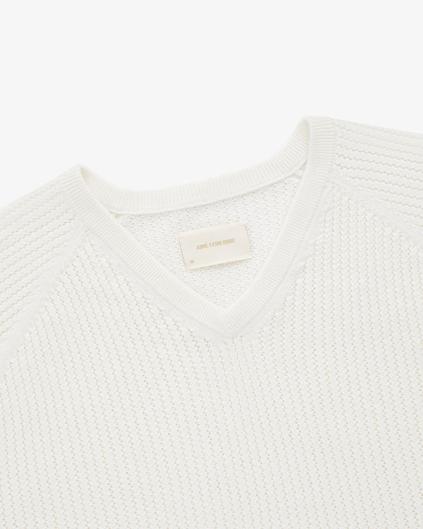 Pointelle Knit Sweater: white V-neck with ribbed trim, shown from above with a beige label inside the collar.