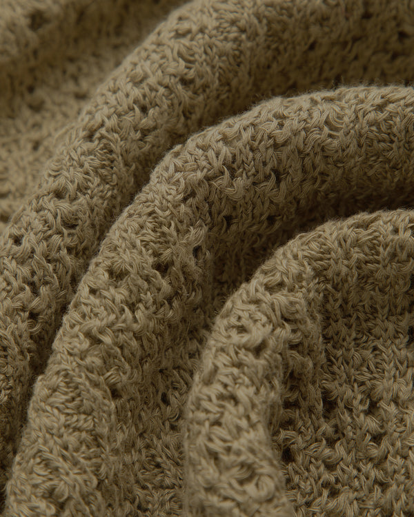 A close-up of the Checkered Crewneck Sweater’s light brown knit, showing textured rows and soft folds.