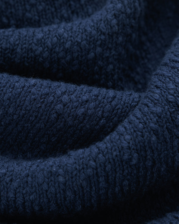 Close-up of Nautical Rollneck Sweater in dark blue knit, highlighting textured stitches and soft, gentle folds.