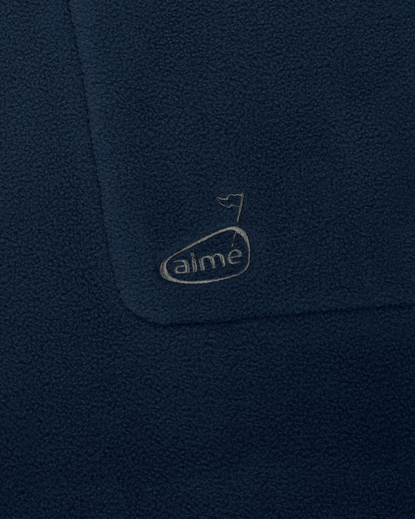Close-up of ALD Golf Fleece Vest in dark blue with an embroidered “aime” logo and small flag above it.