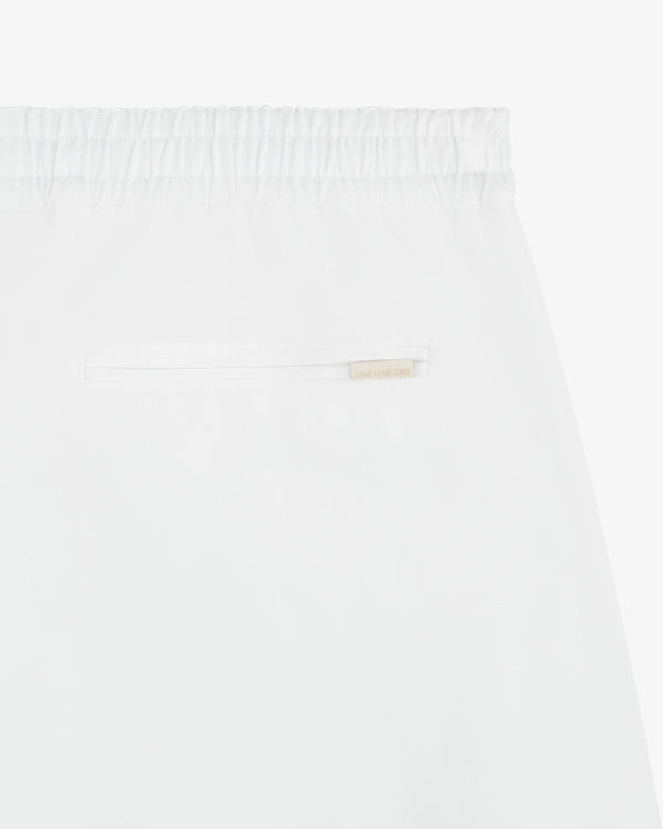 Close-up of the Linen Leisure Pant’s white elastic waistband, single back pocket, and beige label above the pocket.