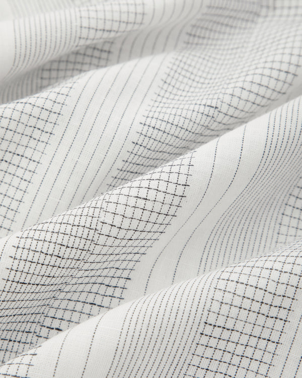 Fil Coupé Leisure Pant in white fabric with thin black grid, softly draped and lightly wrinkled.