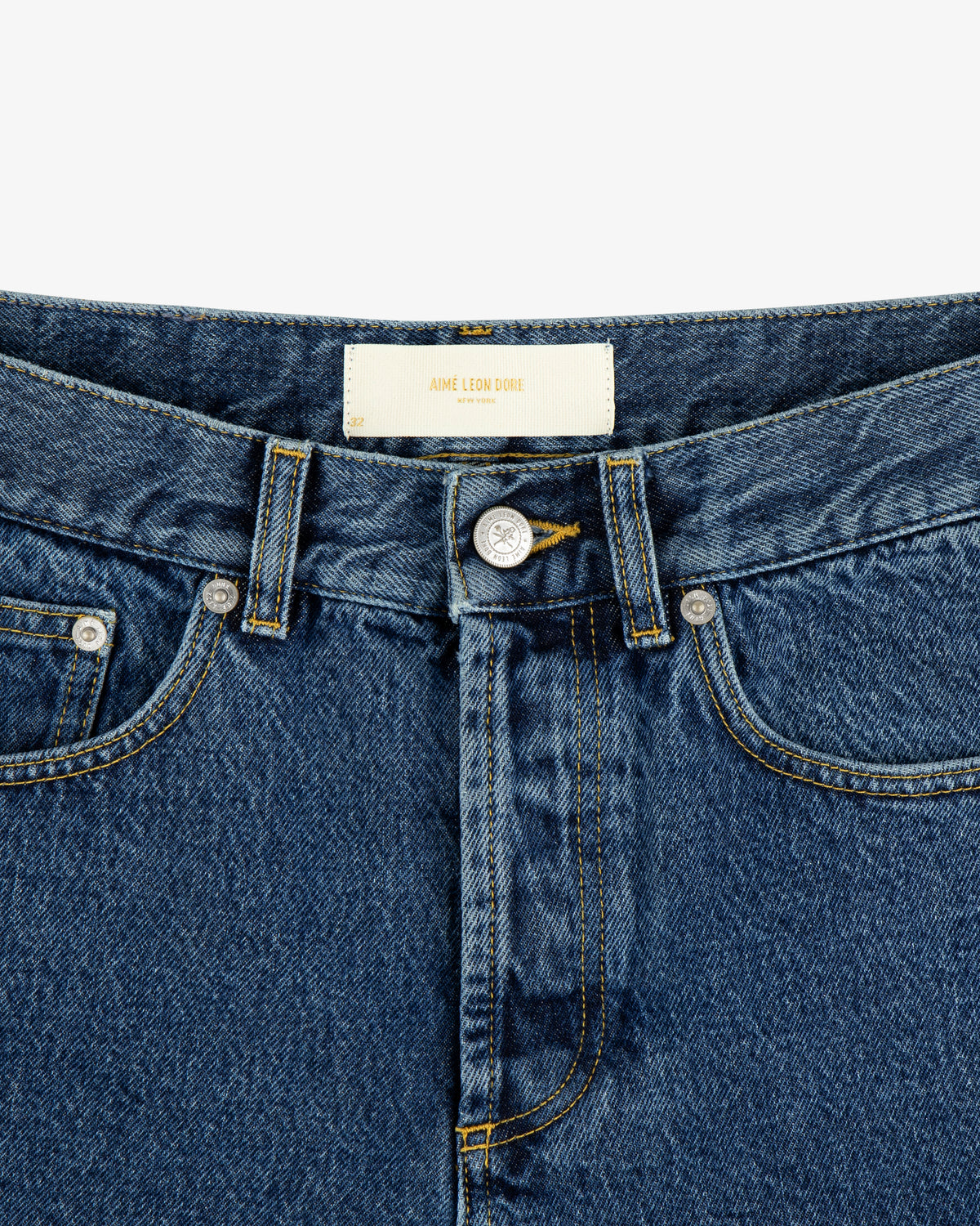 Close-up of ALD Straight Fit Denim in blue with a button fly, front pockets, and a white waistband label.