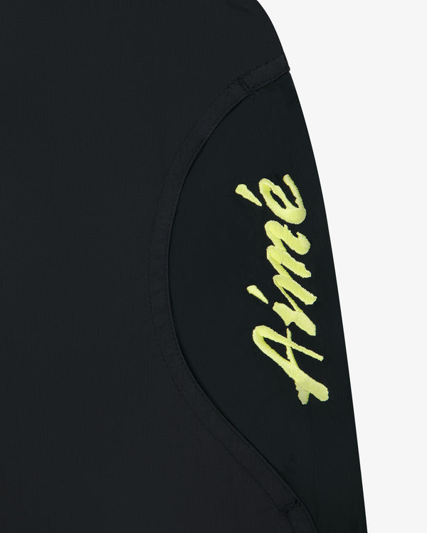 Black Paneled Sport Short with ‘Aimé’ in yellow cursive on a curved fabric panel.