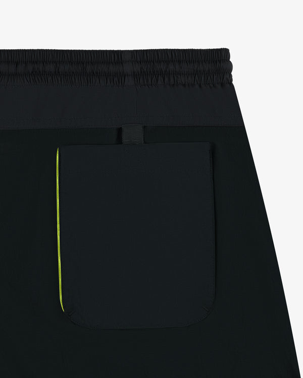 Close-up of Paneled Sport Short in black with elastic waistband, back pocket, and small yellow side accent.