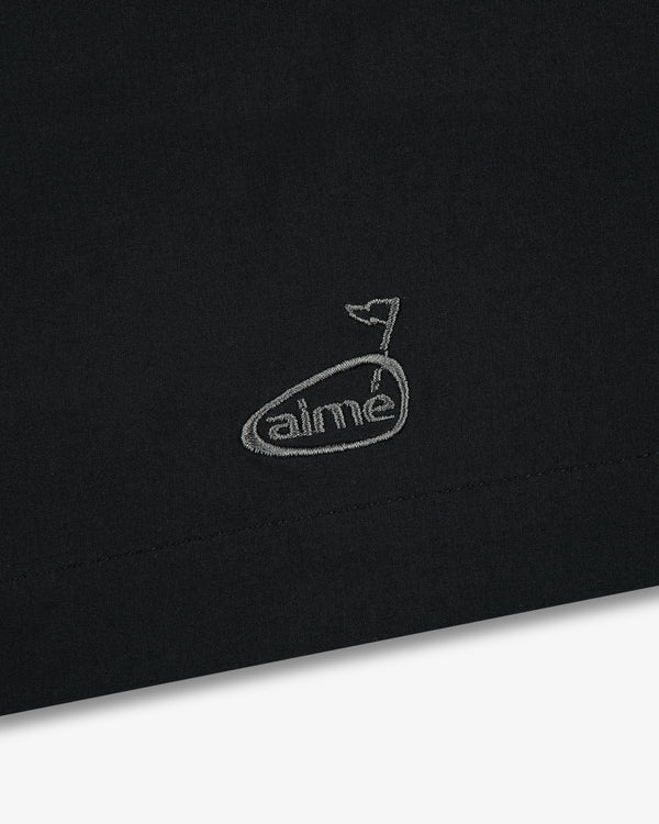 Black fabric with a small, white embroidered whale above “aimé” on the ALD Golf Performance Short.