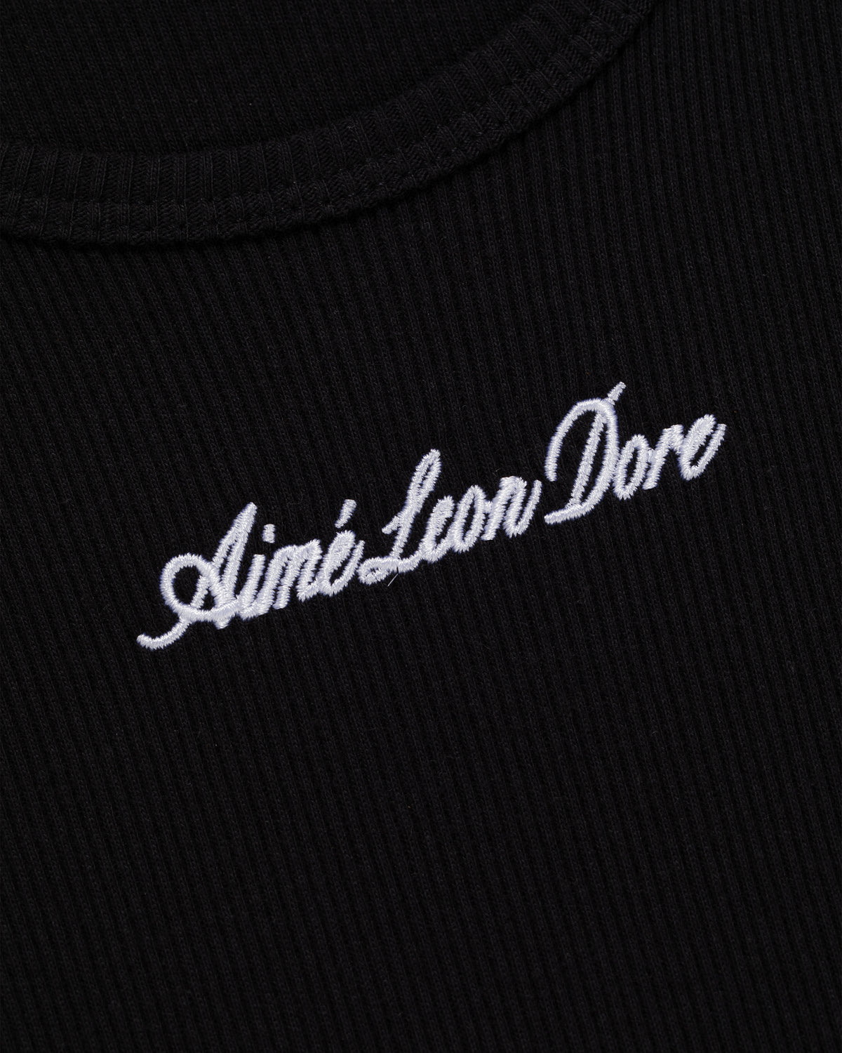 Close-up of black ribbed Embroidered Logo Tank Top with Aimé Leon Dore in white script.