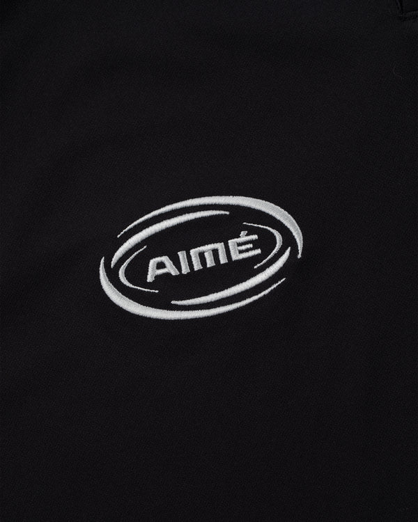 Black fabric Team Leon Performance Jersey with a white AIMÉ logo embroidered in a circular swoosh design.