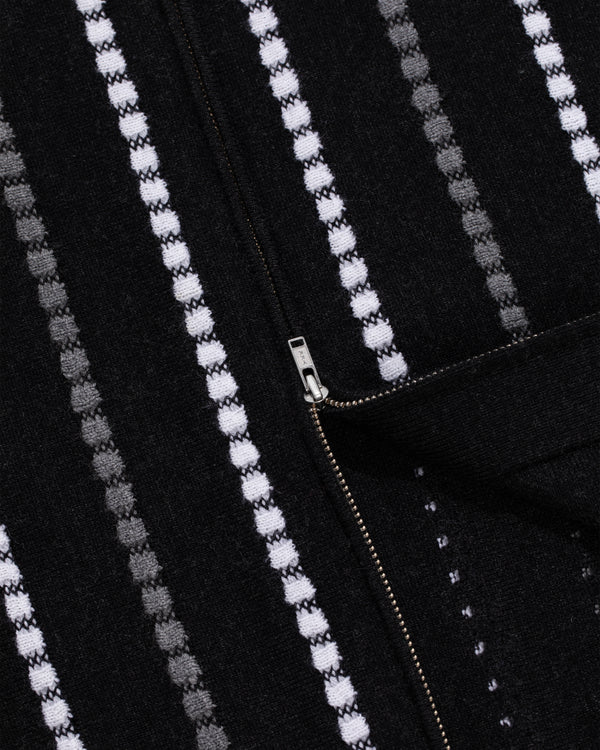 Close-up of Jacquard Stripe Polo Cardigan: black fabric with white and gray dotted stripes, visible metal zipper.