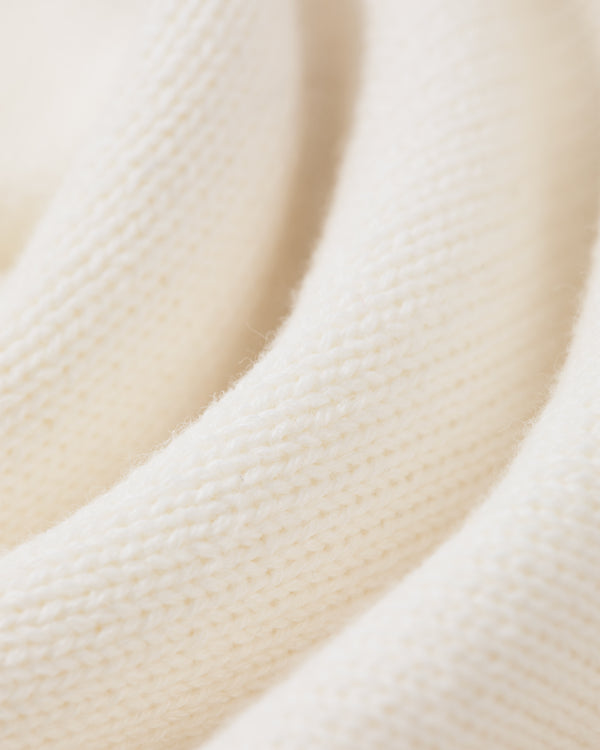 Close-up of Heritage Mockneck Sweater’s soft, cream knit fabric with visible texture and gentle folds.