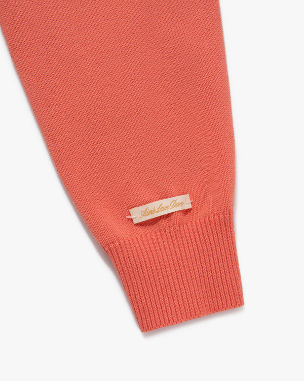 Coral Heritage Mockneck Sweater sleeve with small beige Aimé Leon Dore tag near the ribbed cuff.