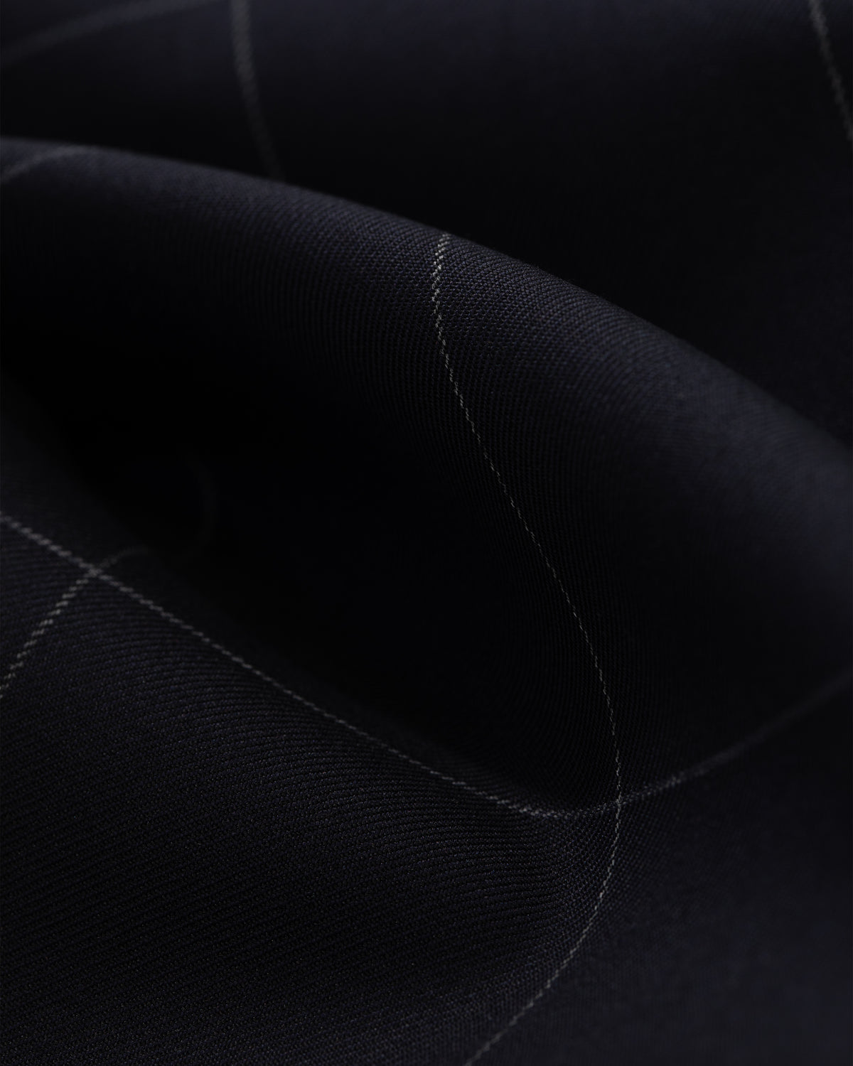A close-up of the Windowpane Elasticated Waist Suit Trouser shows dark fabric with a subtle light grid and gentle folds.