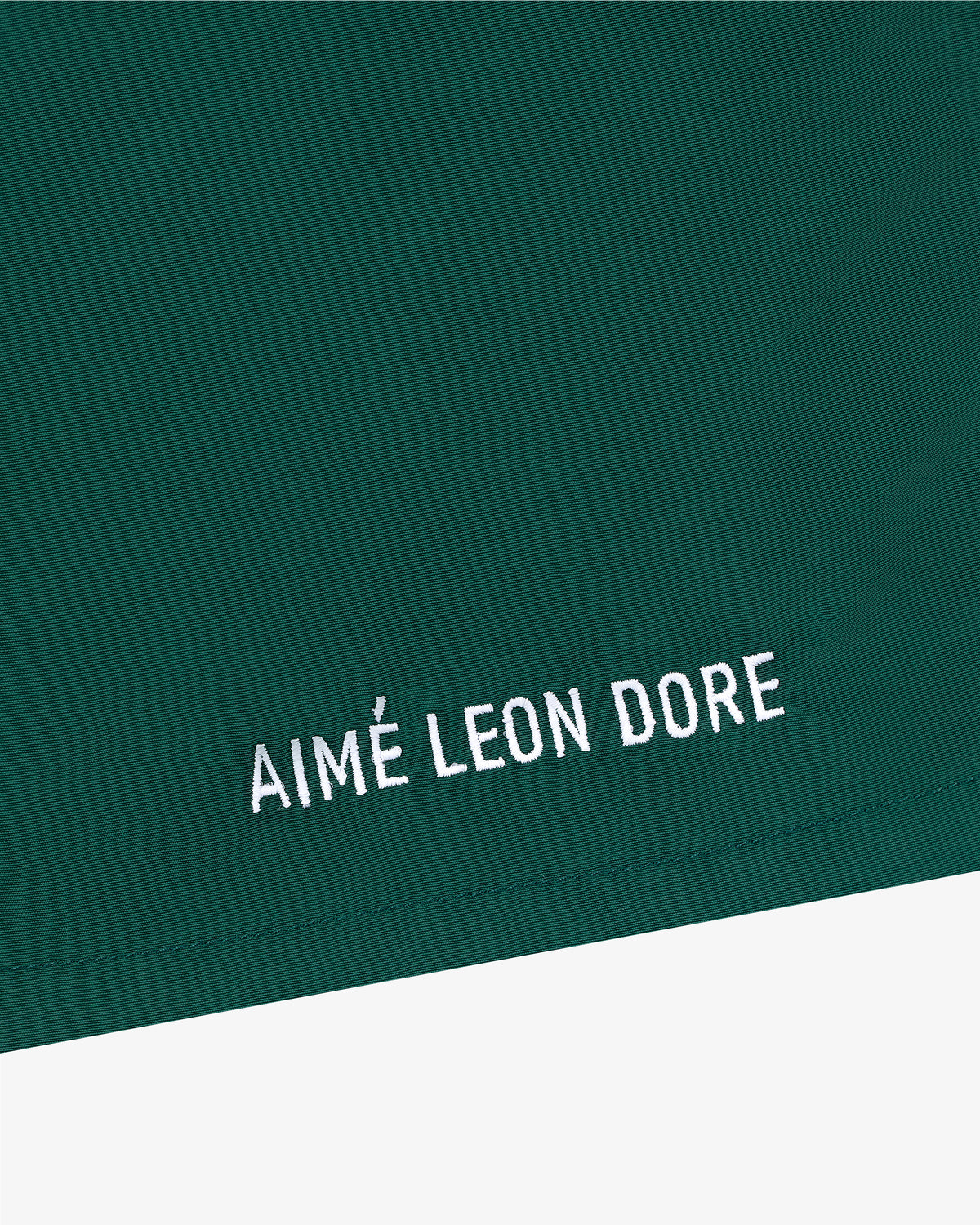 Green Core Nylon Short with white AIMÉ LEON DORE embroidery in a minimalist style near the bottom edge.