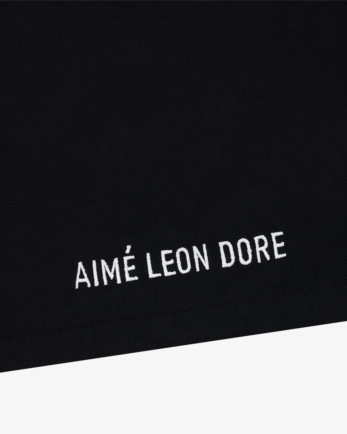 Black Core Nylon Short with white AIMÉ LEON DORE embroidery near the hem.