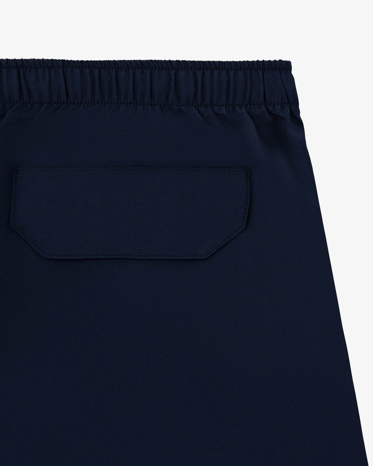 Close-up of the Core Nylon Short in navy blue, featuring an elastic waistband and a back flap pocket.