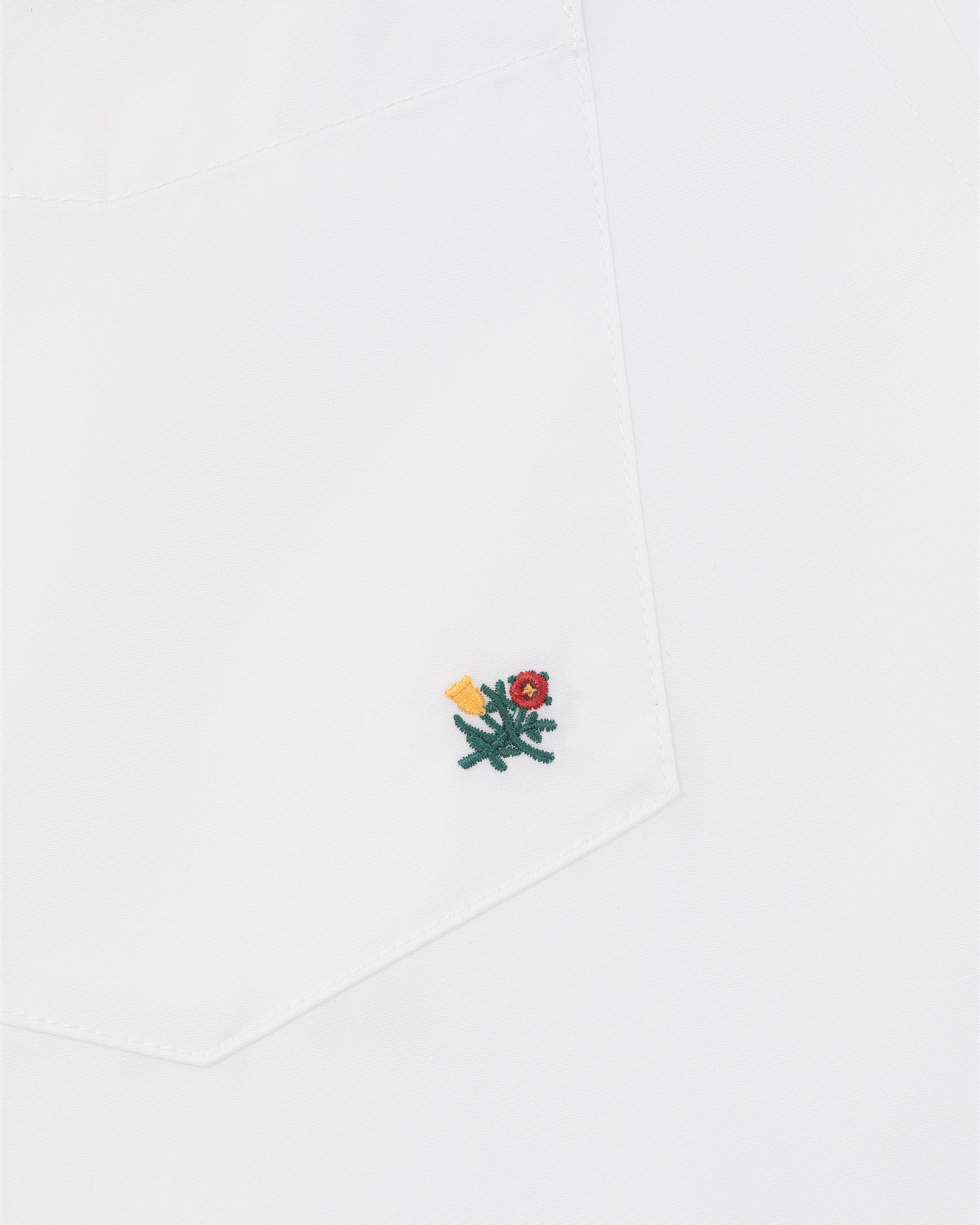Crest Oxford Shirt with white pocket, small green flower embroidery, red center, and yellow detail near the corner.