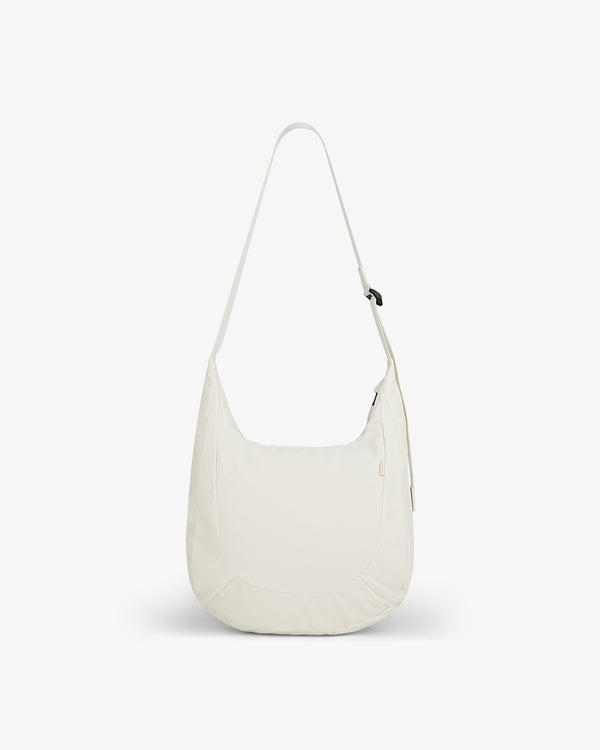 The Nylon Messenger Bag is a minimalist, off-white shoulder bag with a long strap and zippered top.