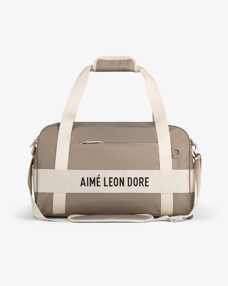 Nylon Duffle Bag in beige with white straps and "AIMÉ LEON DORE" on front, shown on a white background.
