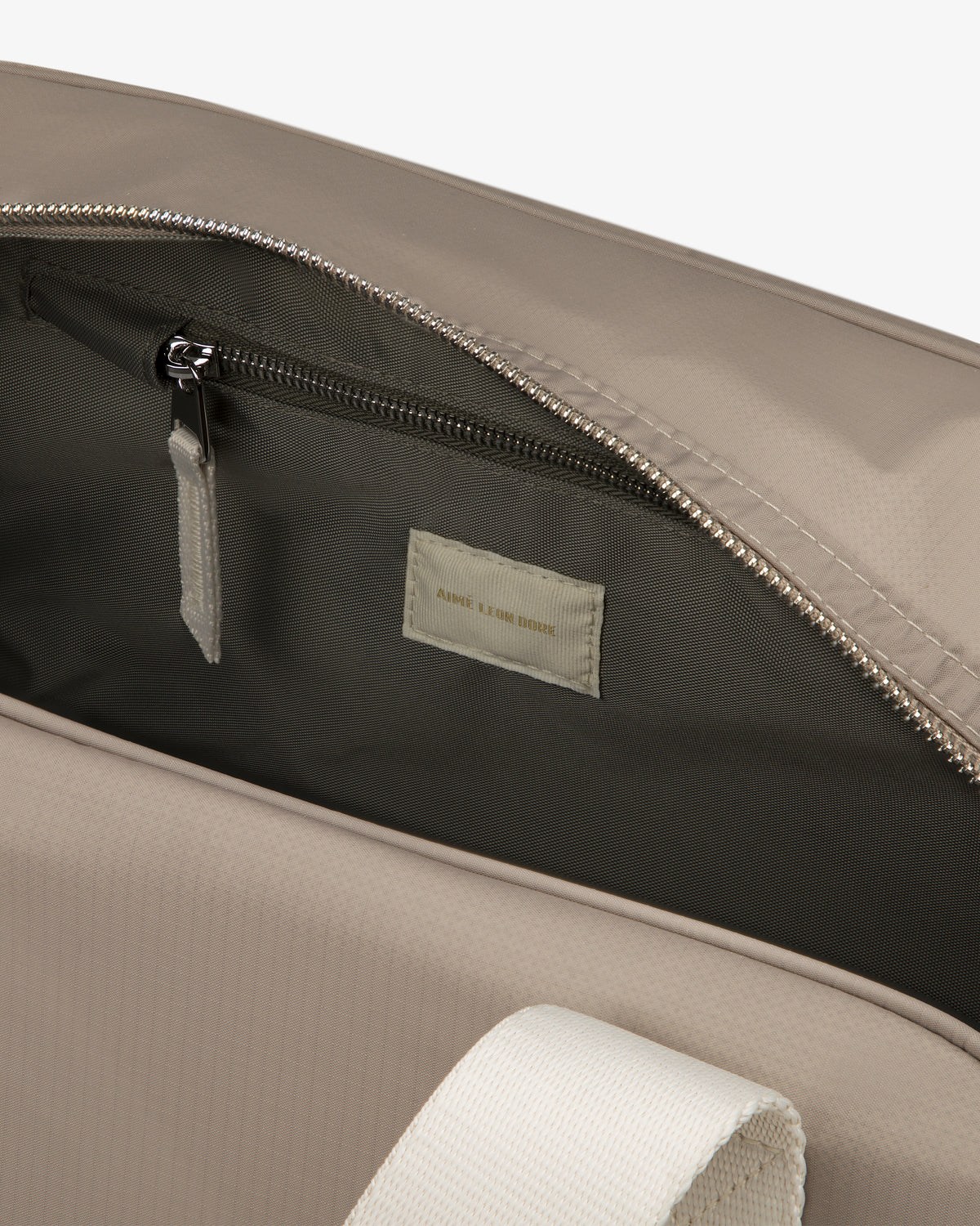 Close-up of an open Nylon Duffle Bag showing a zippered inner pocket and small fabric label inside.