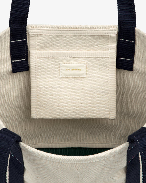 Small Crest Contrast Tote Bag with navy handles, visible white stitching, and a small interior pocket.