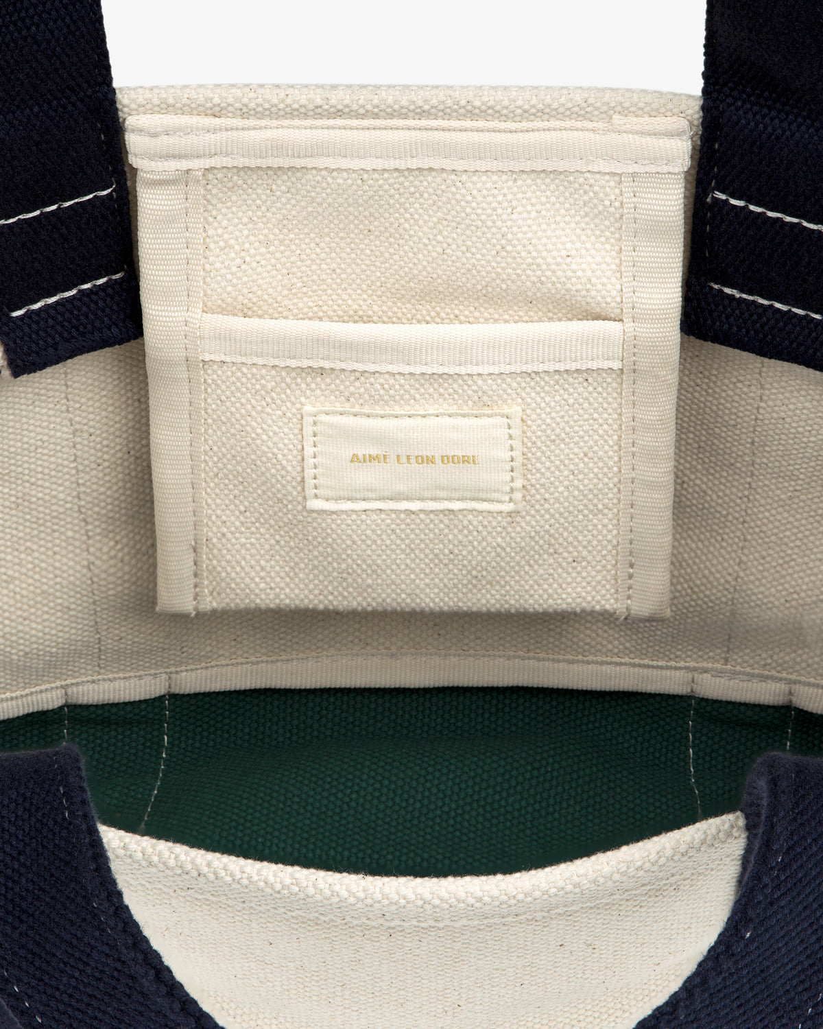 Interior of the Mini Crest Contrast Tote Bag with a small pocket and gold-stitched AIME LEON DORE label.