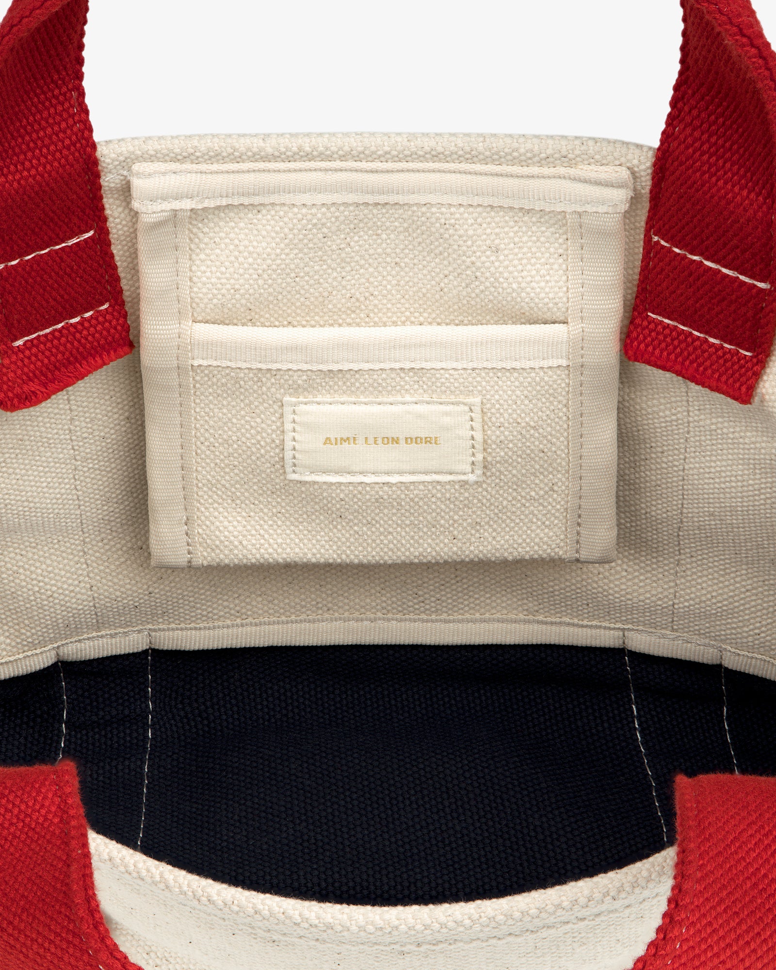 Mini Crest Contrast Tote Bag: cream canvas, red handles, interior pocket with Aime Leon Dore gold label.