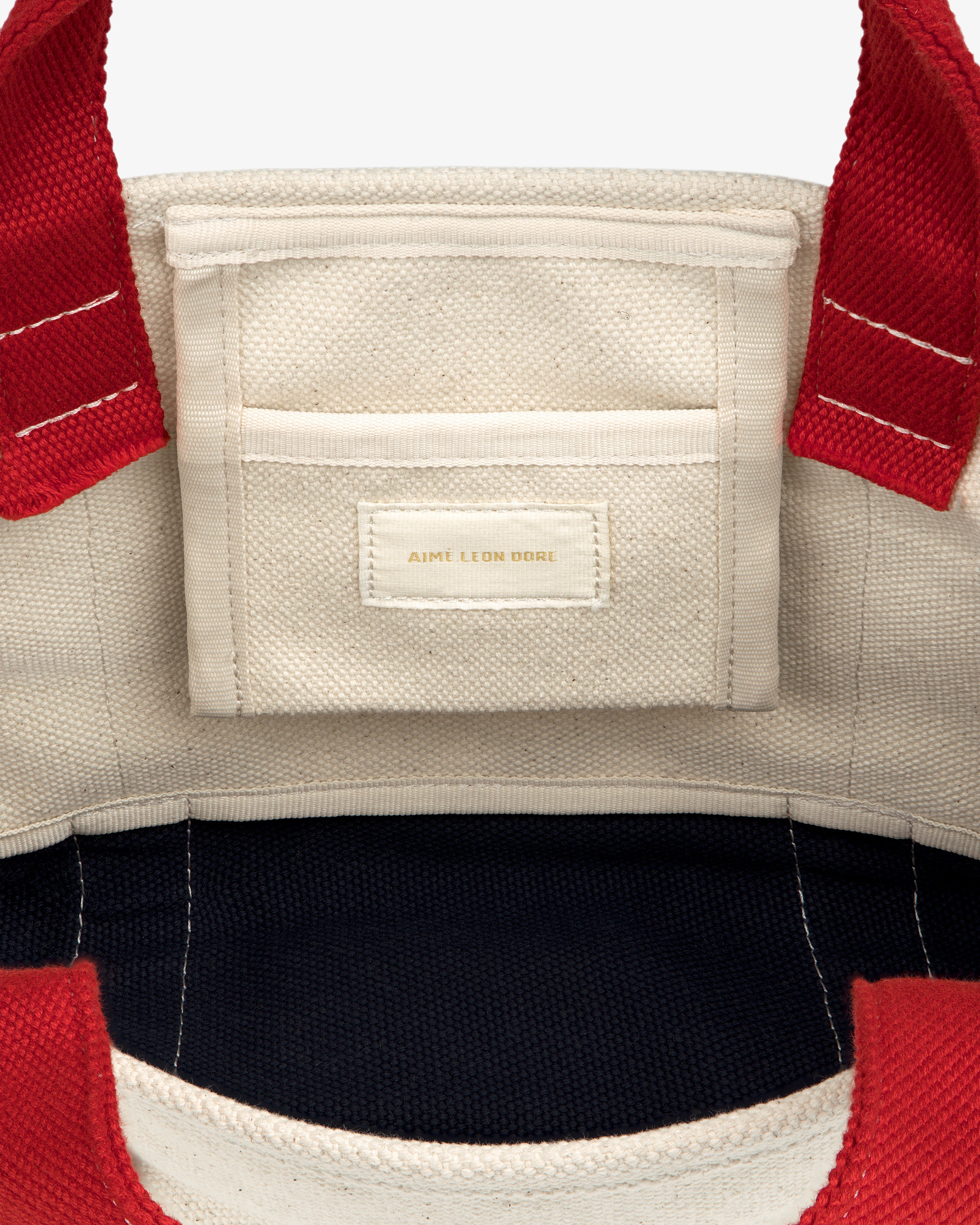 Mini Crest Contrast Tote Bag: cream canvas, red handles, interior pocket with Aime Leon Dore gold label.