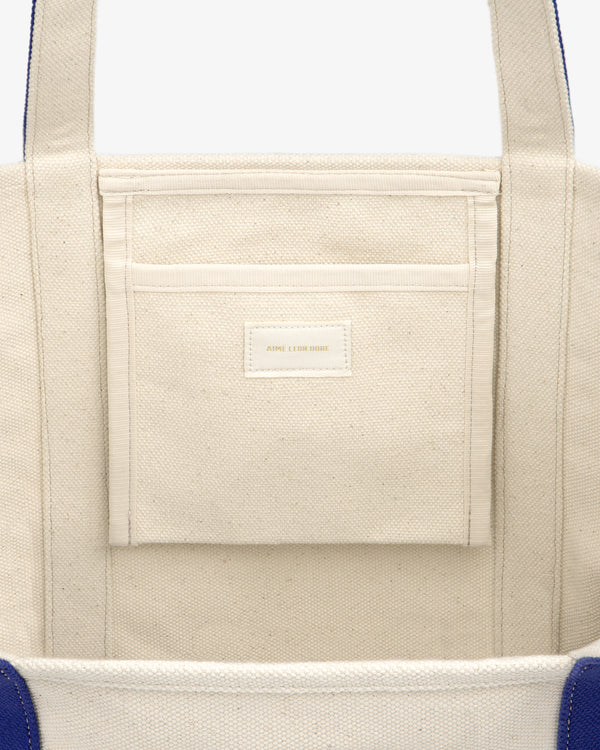 Krylon Tote Bag: Beige canvas with blue side accents and an interior stitched pocket.