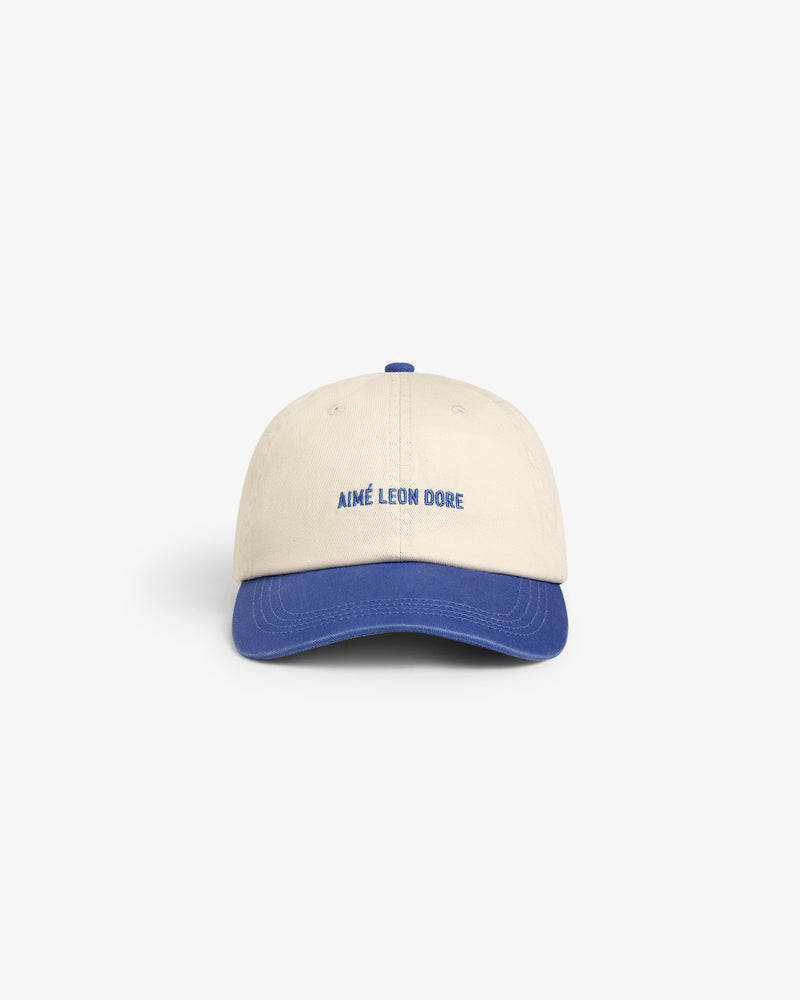 Washed Chino Hat in beige with blue brim and AIMÉ LEON DORE embroidered in blue on the front.