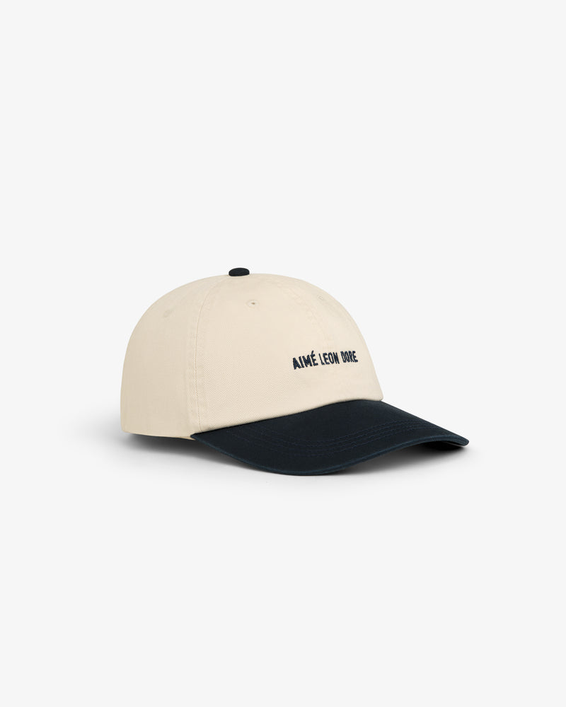 Washed Chino Hat in beige with black brim and "AIMÉ LEON DORE" embroidered in black on the front.