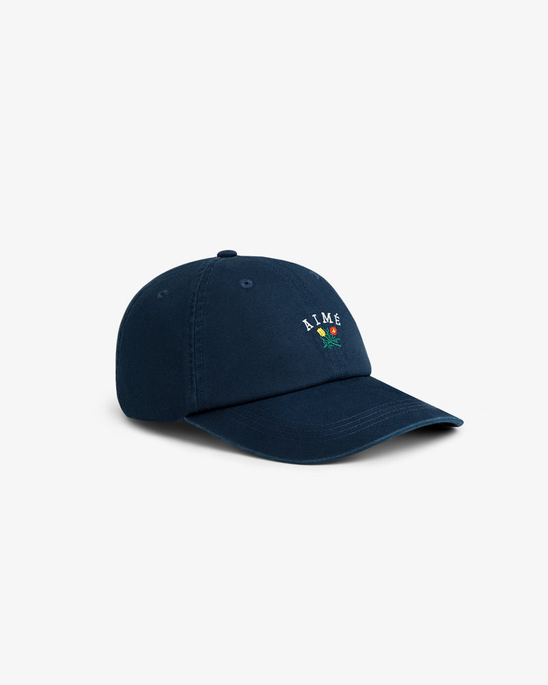 Crest Logo Hat in navy blue with small flower embroidery and 'AIME' on the front, shown at an angle.