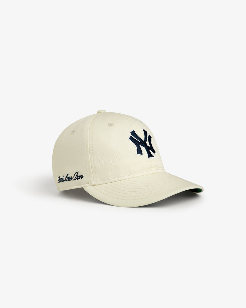 ALD / New Era Yankees Retro Fit Hat in beige with navy Yankees logo and Aimé Leon Dore script on the side.
