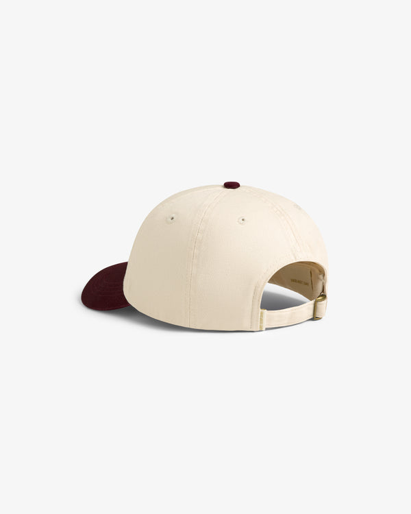 The Cycling Logo Hat is beige with a maroon brim, shown from the back and features an adjustable strap.