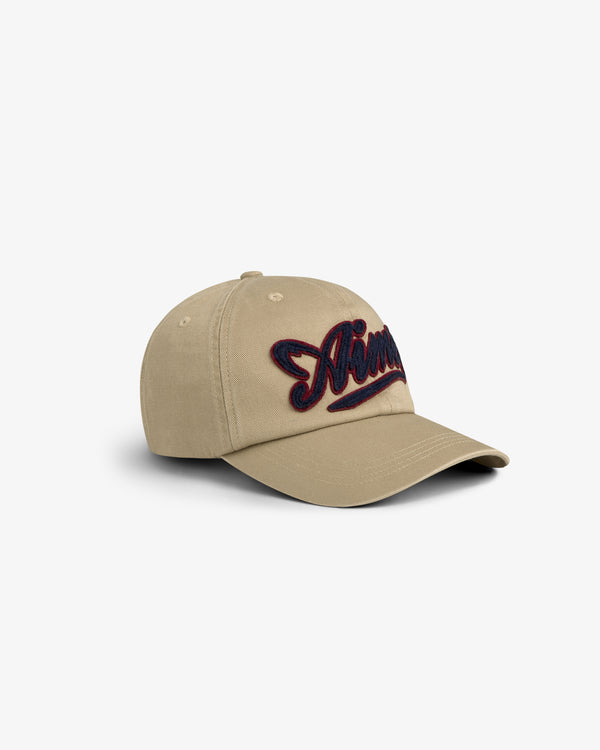 Tan Cycling Logo Hat with curved brim and dark embroidered script on the front, shown on white background.