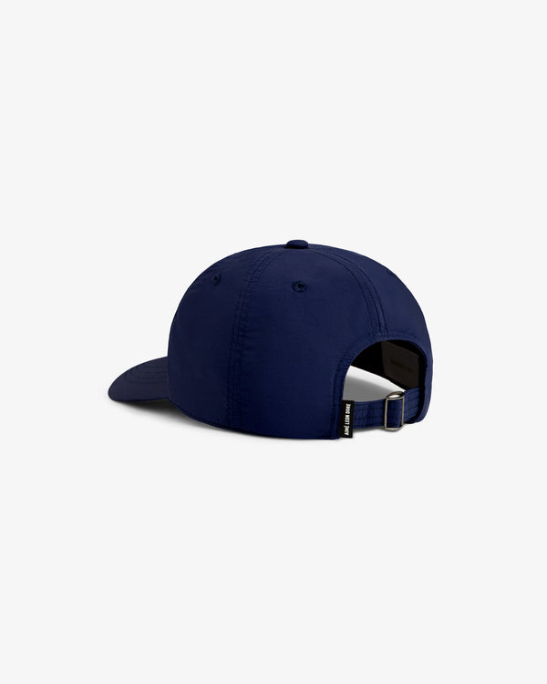 The Nylon Crusher Hat in navy blue is shown from the back with an adjustable strap and a small side tag.