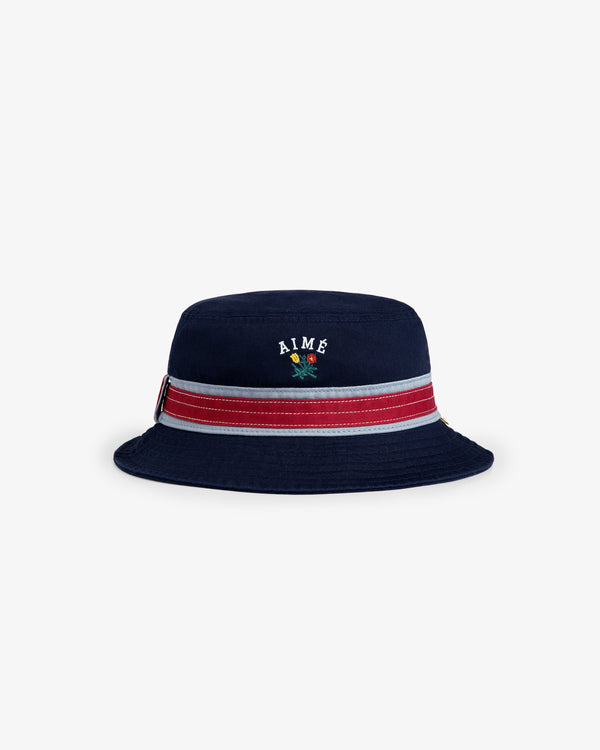 Crest Bucket Hat: Navy blue with a red and white stripe, AIMÉ embroidered above a small parrot on the front.