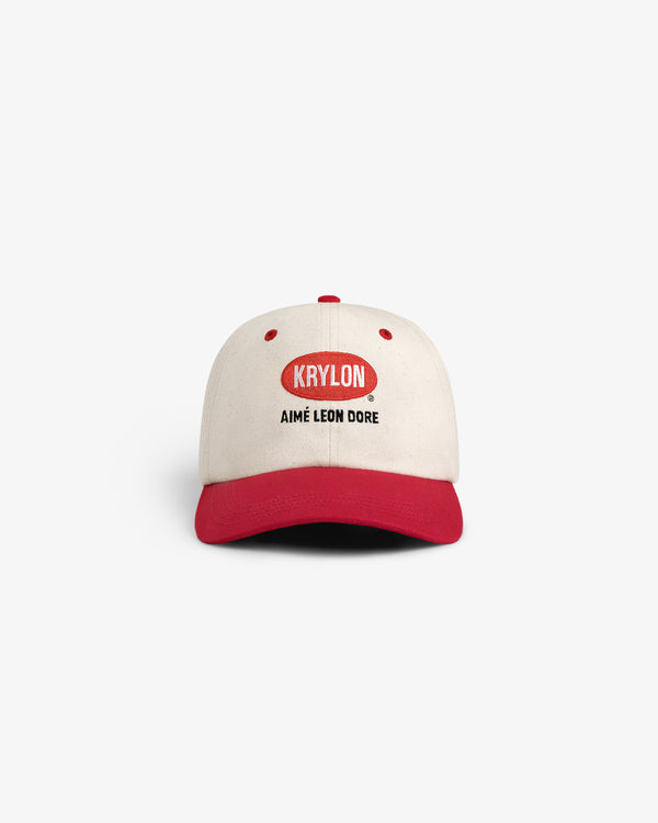 The Krylon Logo Hat is a beige and red baseball cap featuring KRYLON and AIMÉ LEON DORE text on the front.