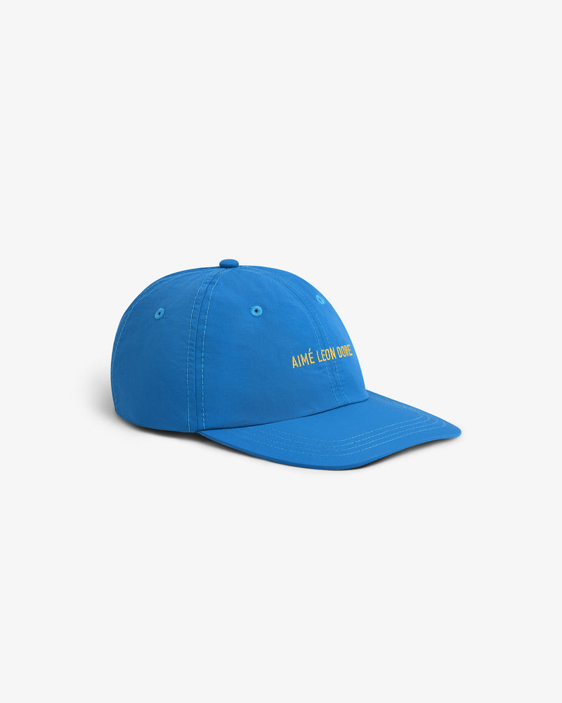 A Nylon Sport Hat in bright blue with yellow AIMÉ LEON DORE embroidery on the front, shown from the side.