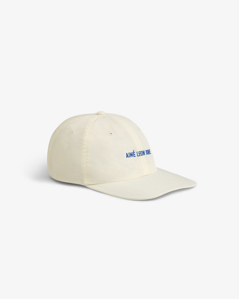 Cream-colored Nylon Sport Hat with blue AIMÉ LEON DORE text on the front, shown angled on a white background.