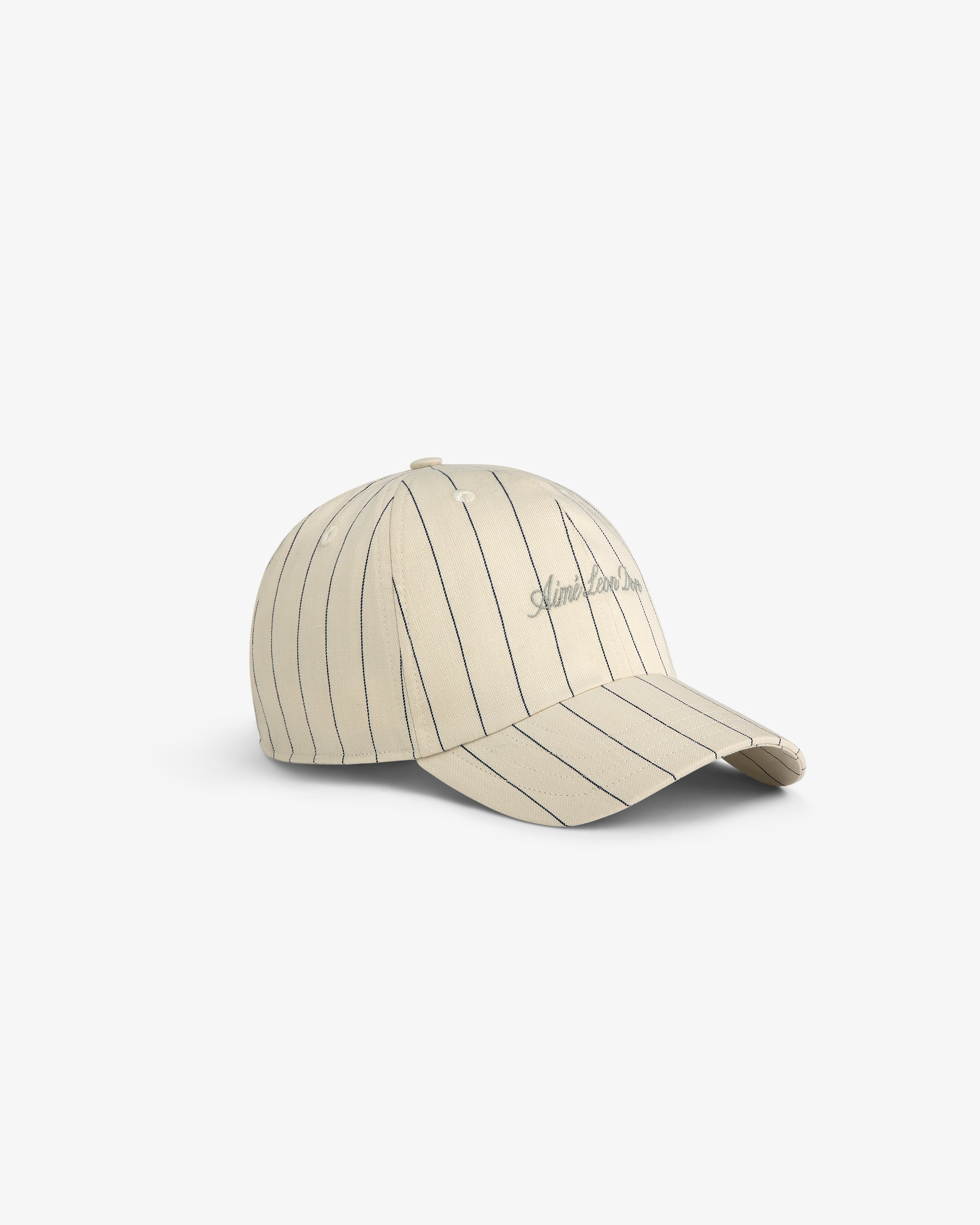 Pinstripe Suiting Hat: Beige baseball cap with thin black stripes and cursive embroidery, shown on white background.