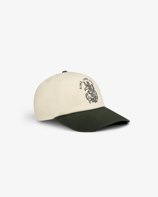 The Saint George Logo Hat is a cream and dark green cap featuring black embroidered graphic and text on the front.