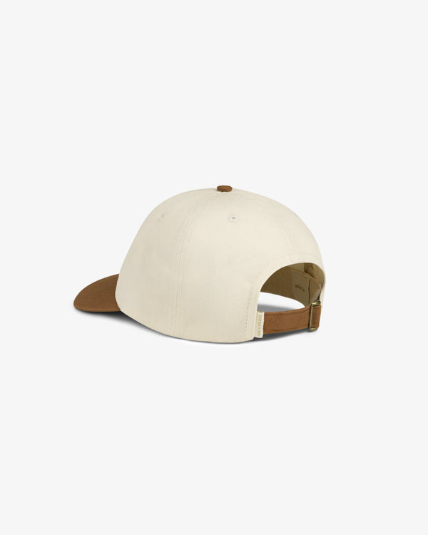 The Saint George Logo Hat is a cream baseball cap with a brown curved brim and adjustable brown strap, shown on white.