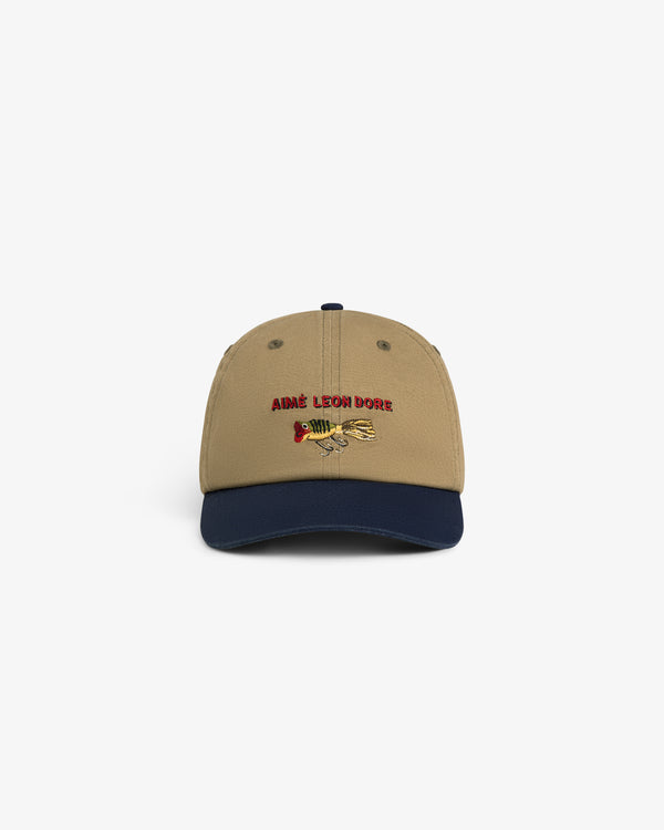 Colorblock Lure Hat: Tan cap with navy brim, AIMÉ LEON DORE and fishing lure graphic embroidered on the front.