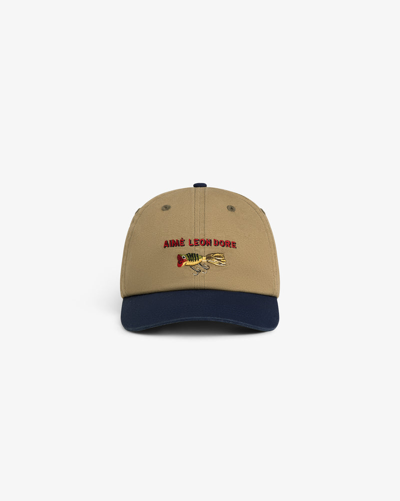 Colorblock Lure Hat: Tan cap with navy brim, AIMÉ LEON DORE and fishing lure graphic embroidered on the front.