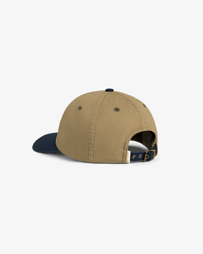 Colorblock Lure Hat in tan with navy brim, shown from the back with adjustable strap and metal clasp.